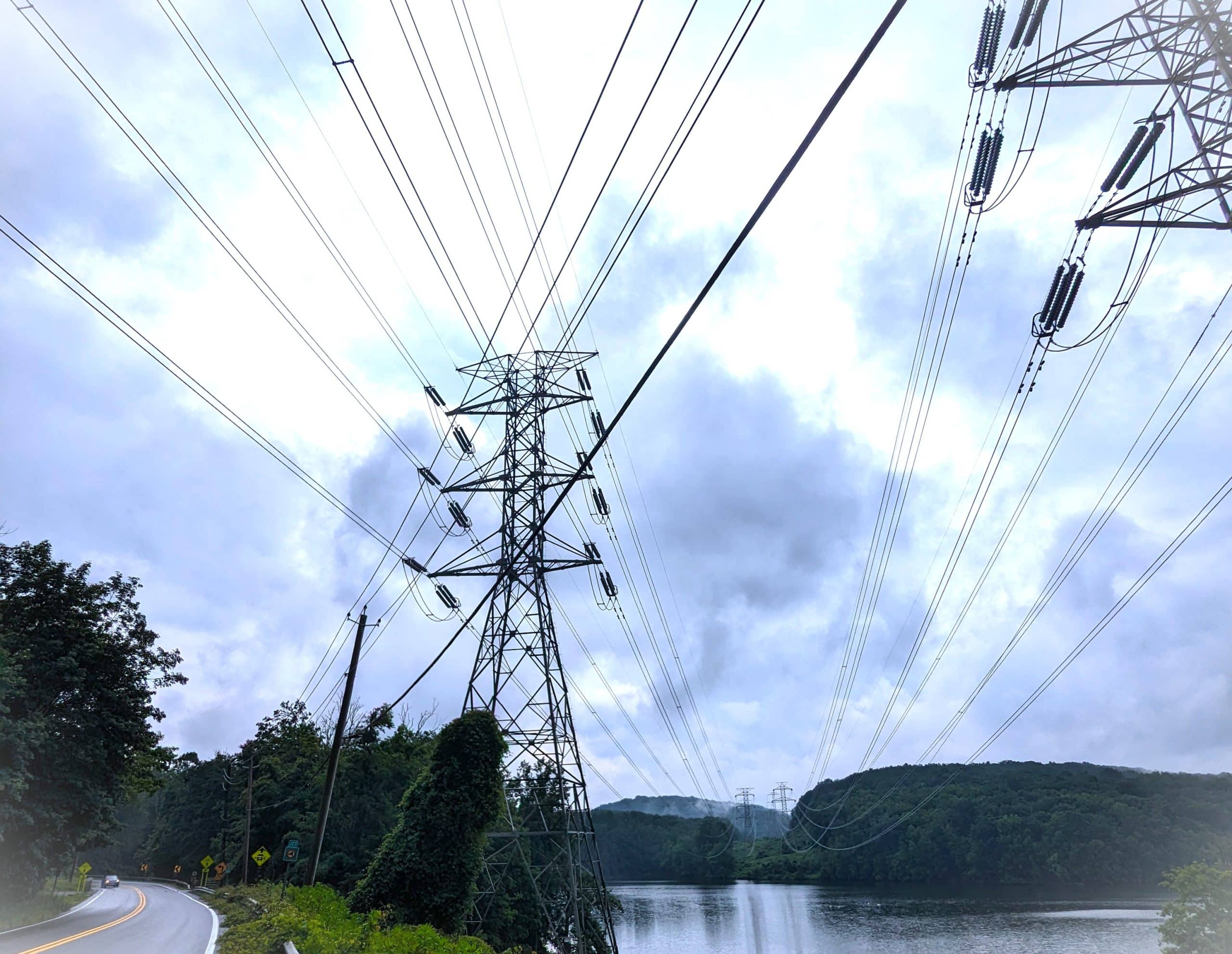 Power lines on a cloudy day stretching over water